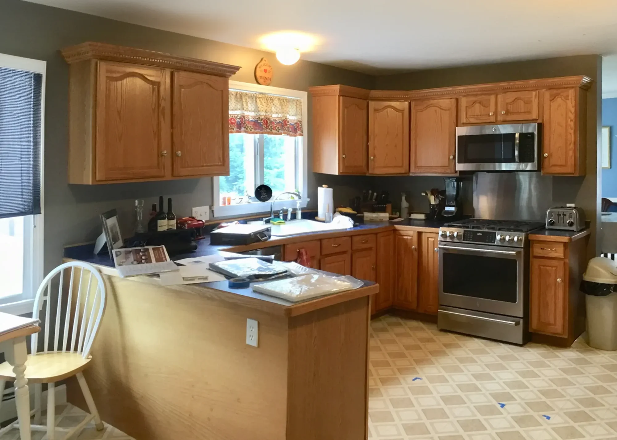 Before photo of a kitchen with wooden cabinets, stainless steel appliances, and a island.