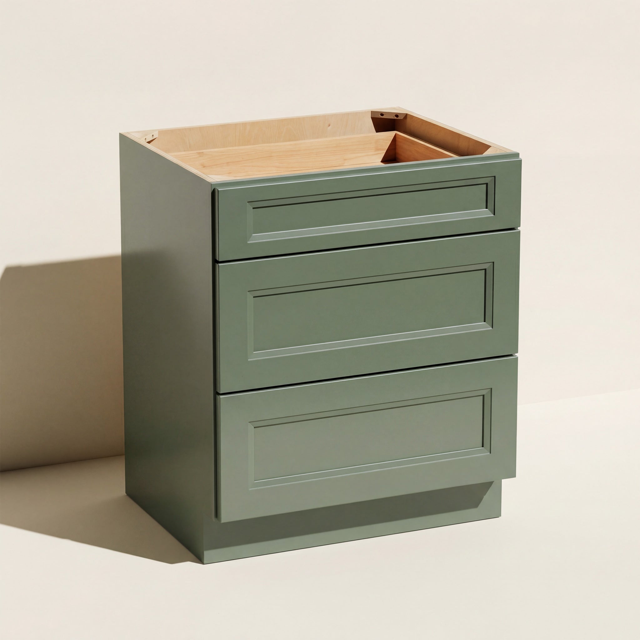 Angled view of a green Belmont beveled Shaker drawer base cabinet with 3 functional drawers.