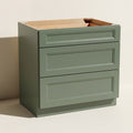 Angled view of a green Belmont beveled Shaker standard base cabinet with 3 drawers.