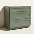 Angled view of a green 36w Belmont beveled Shaker drawer base cabinet with 3 functional drawers.