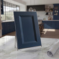 Angled Belmont blue beveled shaker cabinet door sample on a white stone countertop against a contemporary kitchen backdrop.
