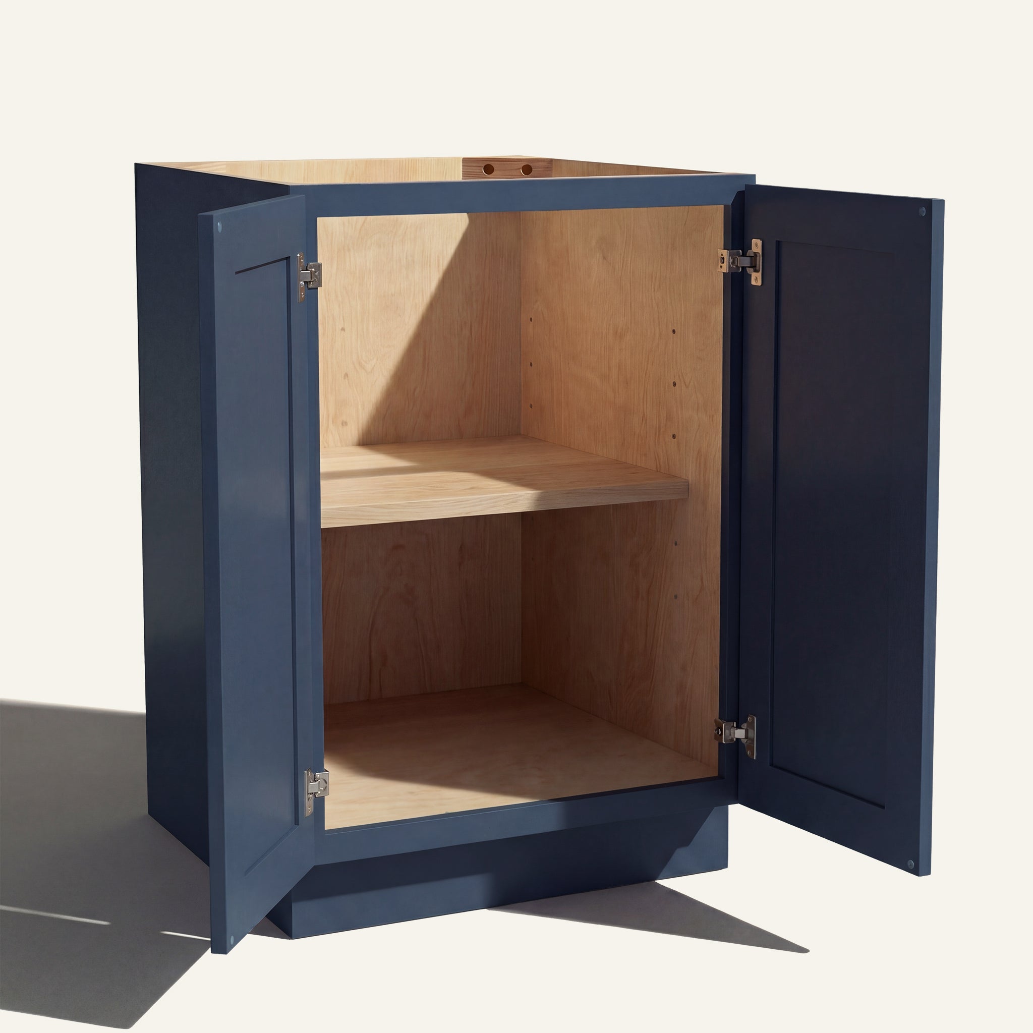 Angled view of a blue Belmont beveled Shaker base cabinet with 2 full height doors open showing wood interior and shelf.