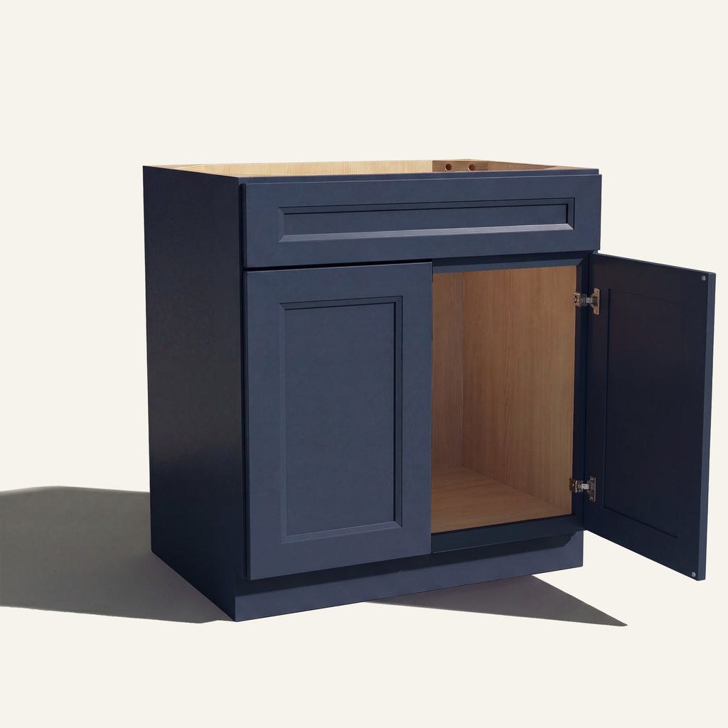Angled view of blue Belmont beveled Shaker single sink vanity, 1 false front, 2 doors with right one open to a wood interior.
