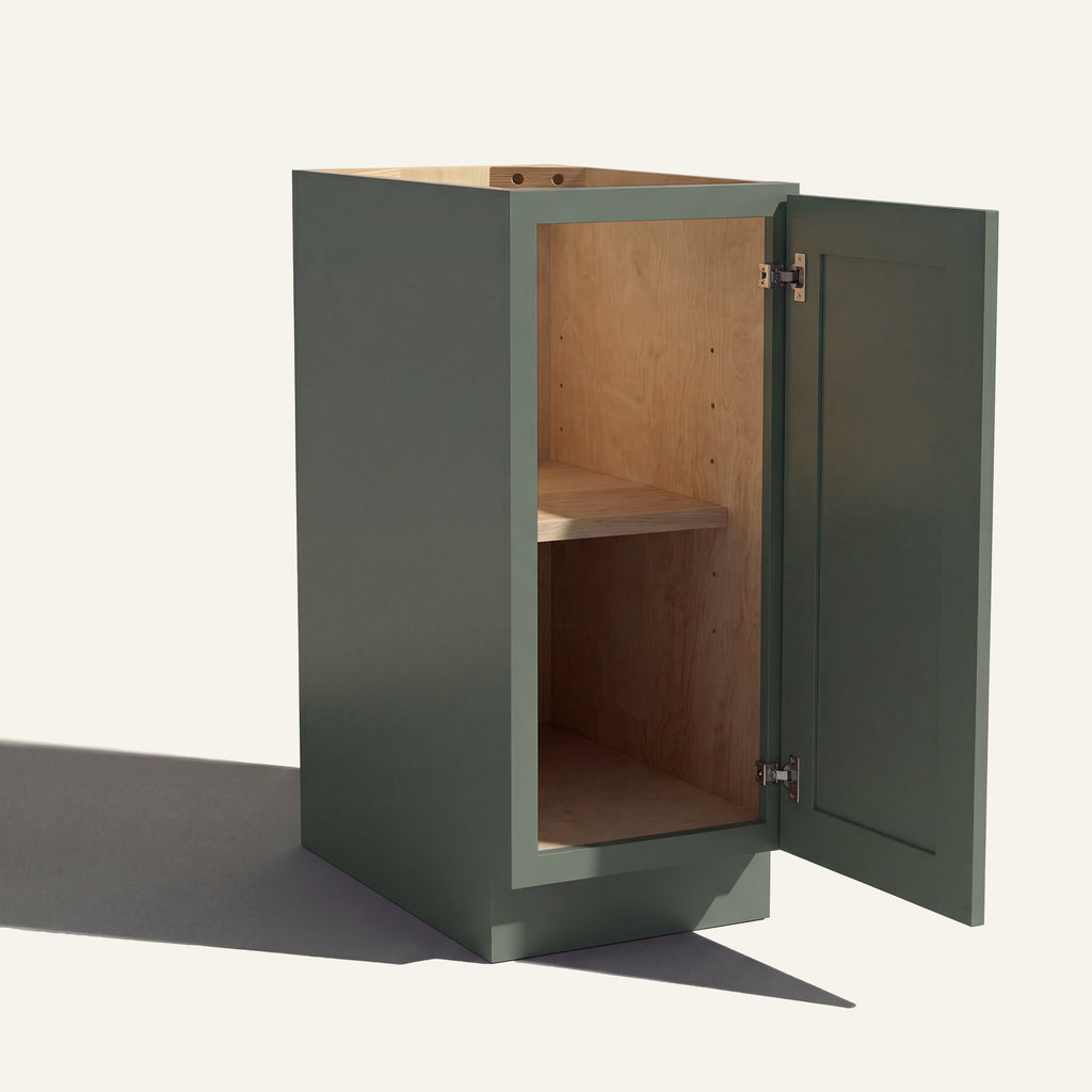 Angled view of a green Belmont beveled Shaker base cabinet with 1 door open showing wood interior and shelf.