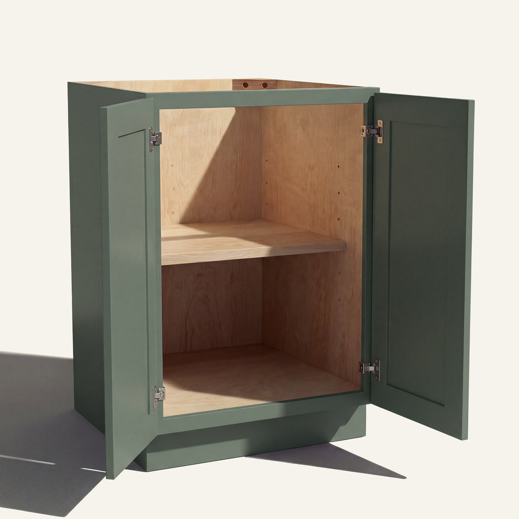 Angled view of a green Belmont beveled Shaker base cabinet with 2 full height doors open showing wood interior and shelf.