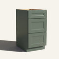 Angled view of a green Belmont beveled Shaker vanity base with 3 drawers stacked.