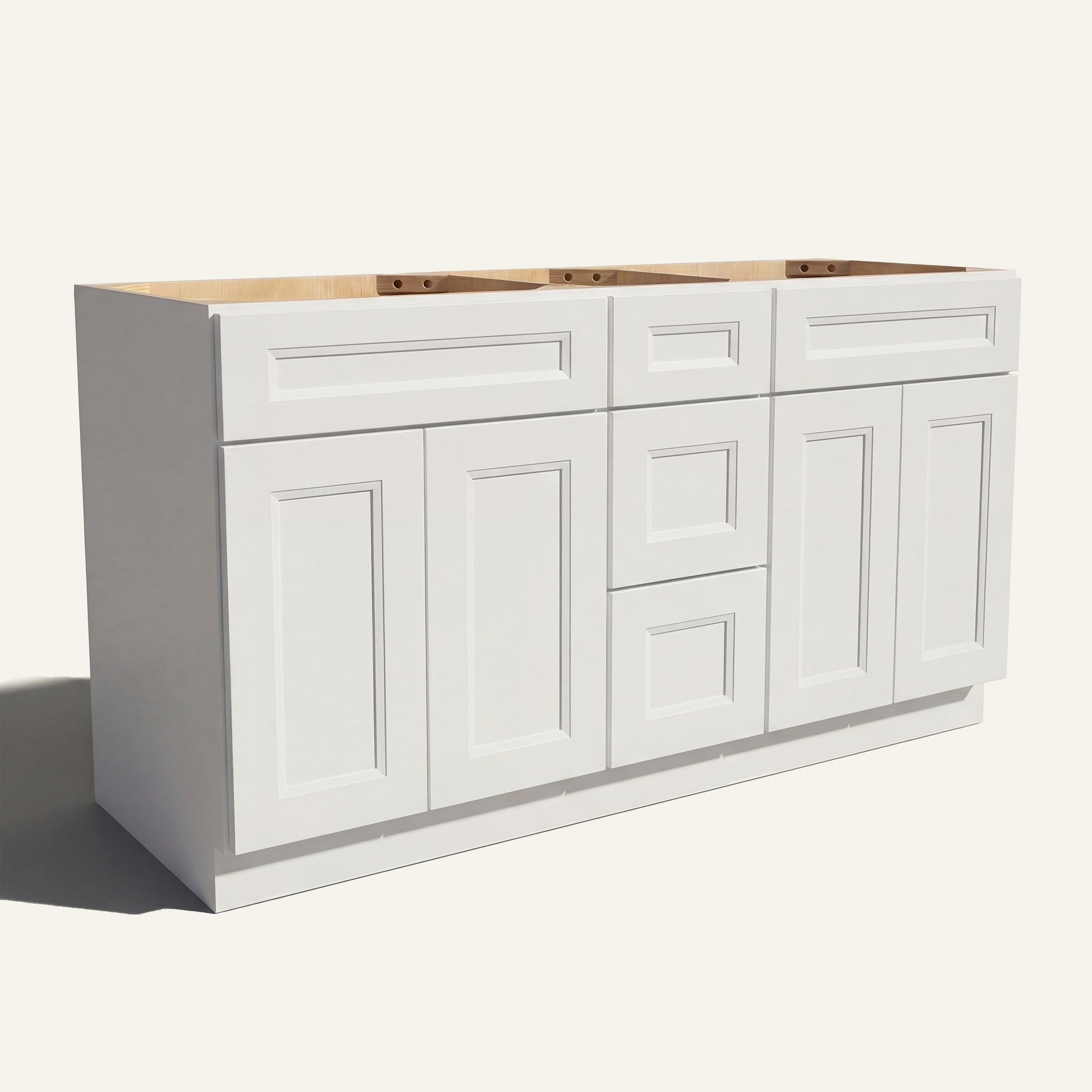 Angled view of a white Belmont beveled Shaker double sink vanity base with 4 doors, 3 drawers, and 2 false drawer fronts.