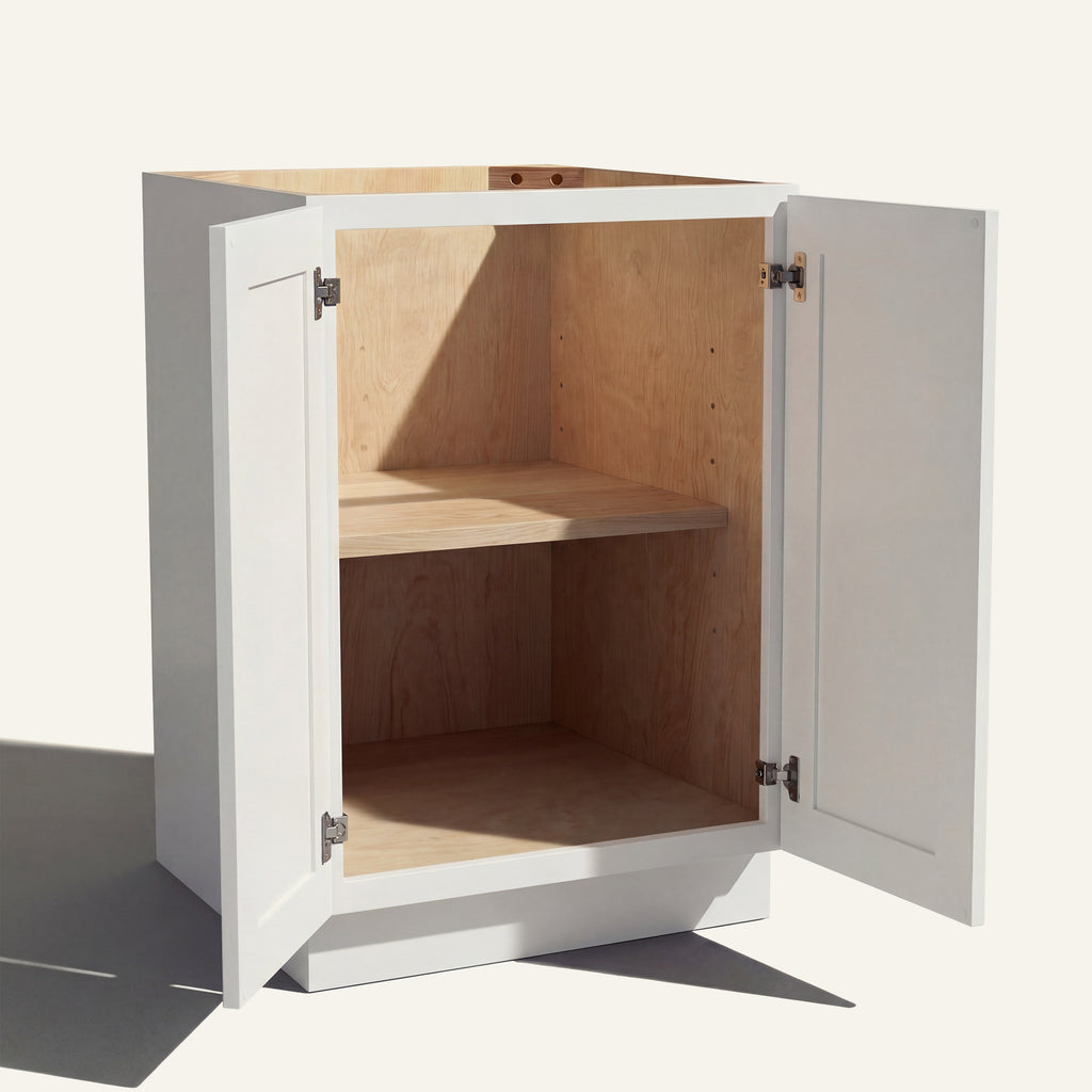 Angled view of a white Belmont beveled Shaker base cabinet with 2 full height doors open showing wood interior and shelf.