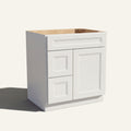 Angled view of a white Belmont beveled shaker single sink vanity with a right-side door and two left-side drawers.