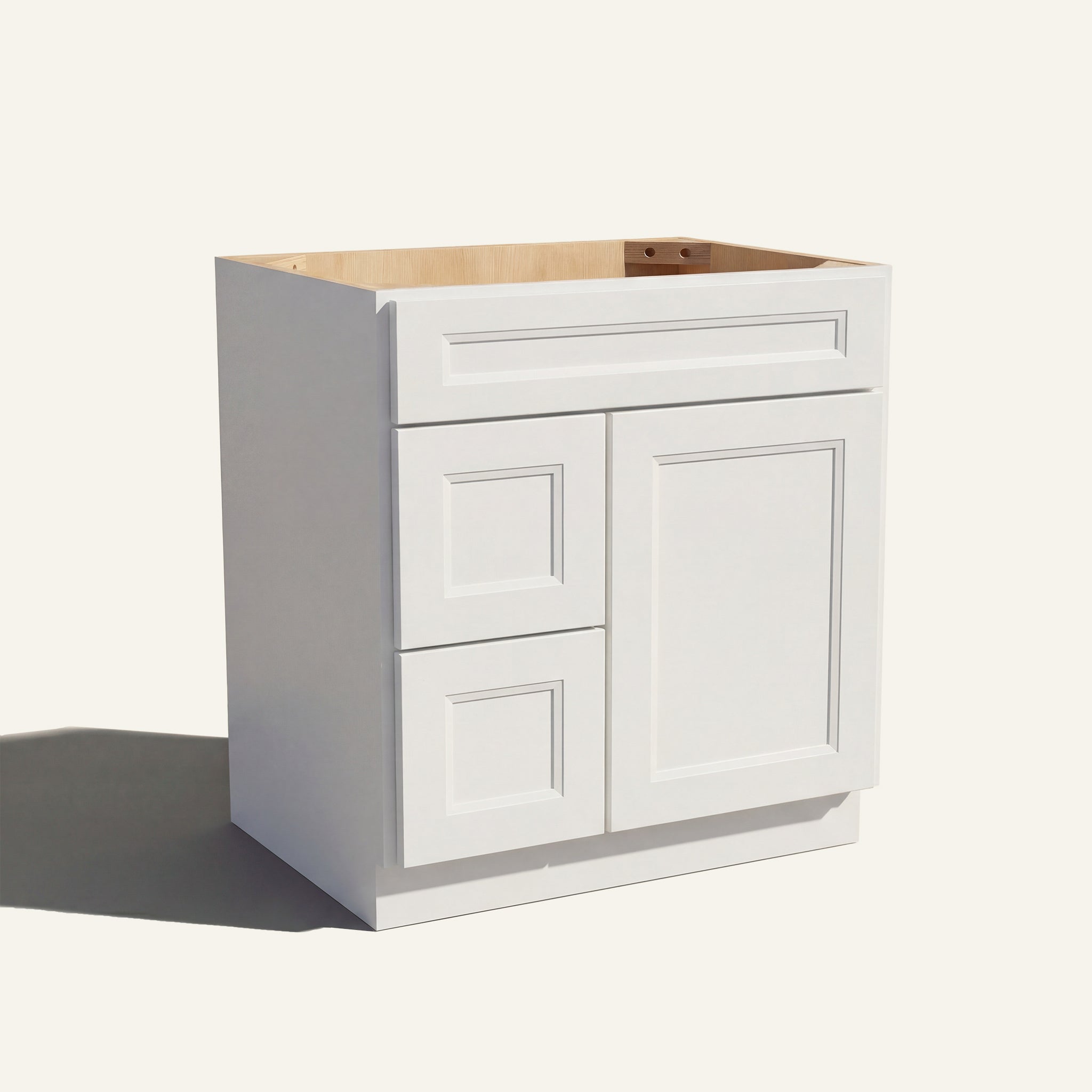 Angled view of a white Belmont beveled shaker single sink vanity with a right-side door and two left-side drawers.