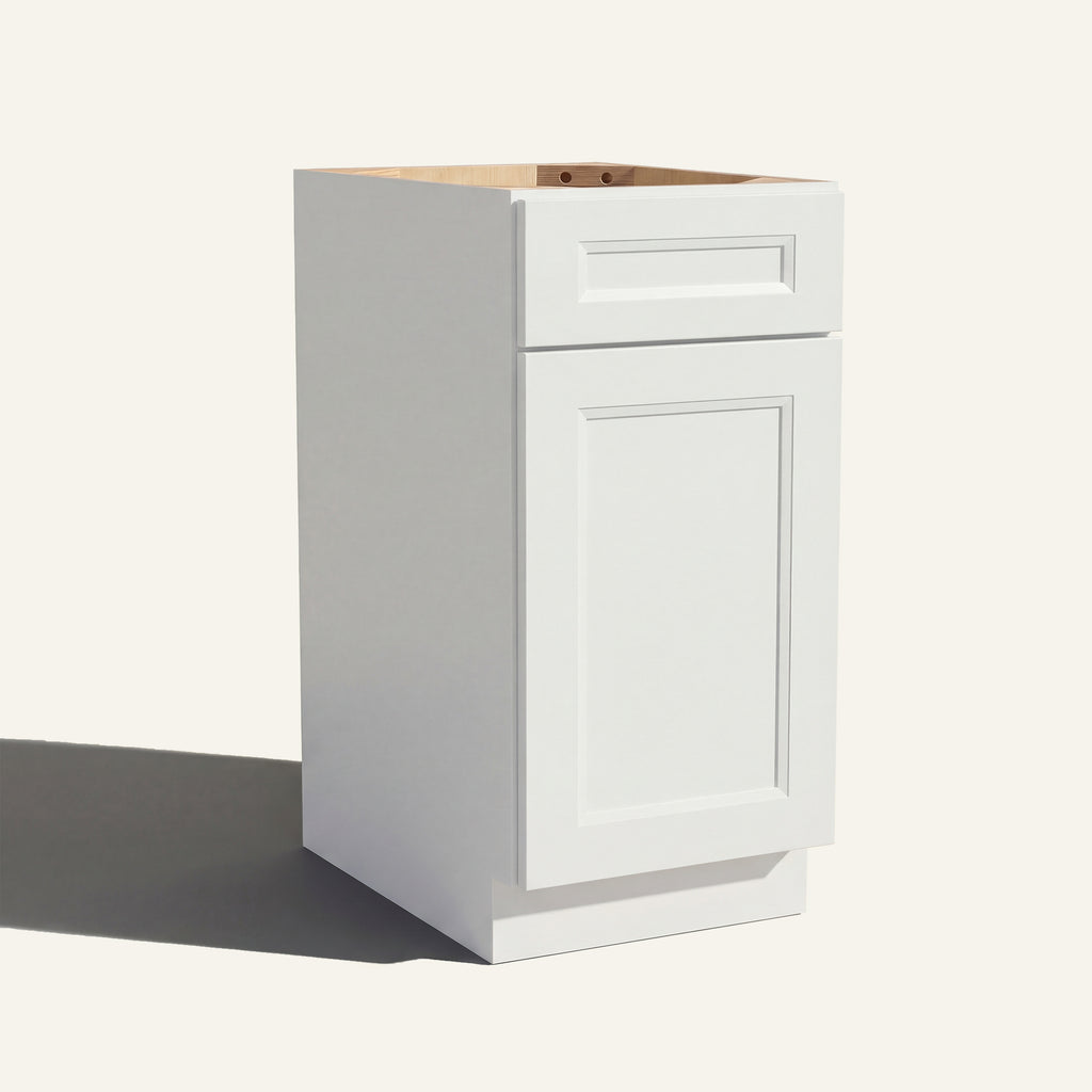 Angled view of a white Belmont beveled Shaker vanity base cabinet with 1 door and 1 drawer.
