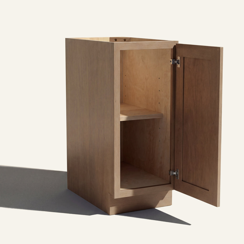 Angled view of a driftwood Seaport Shaker base cabinet with 1 door open showing wood interior and shelf.