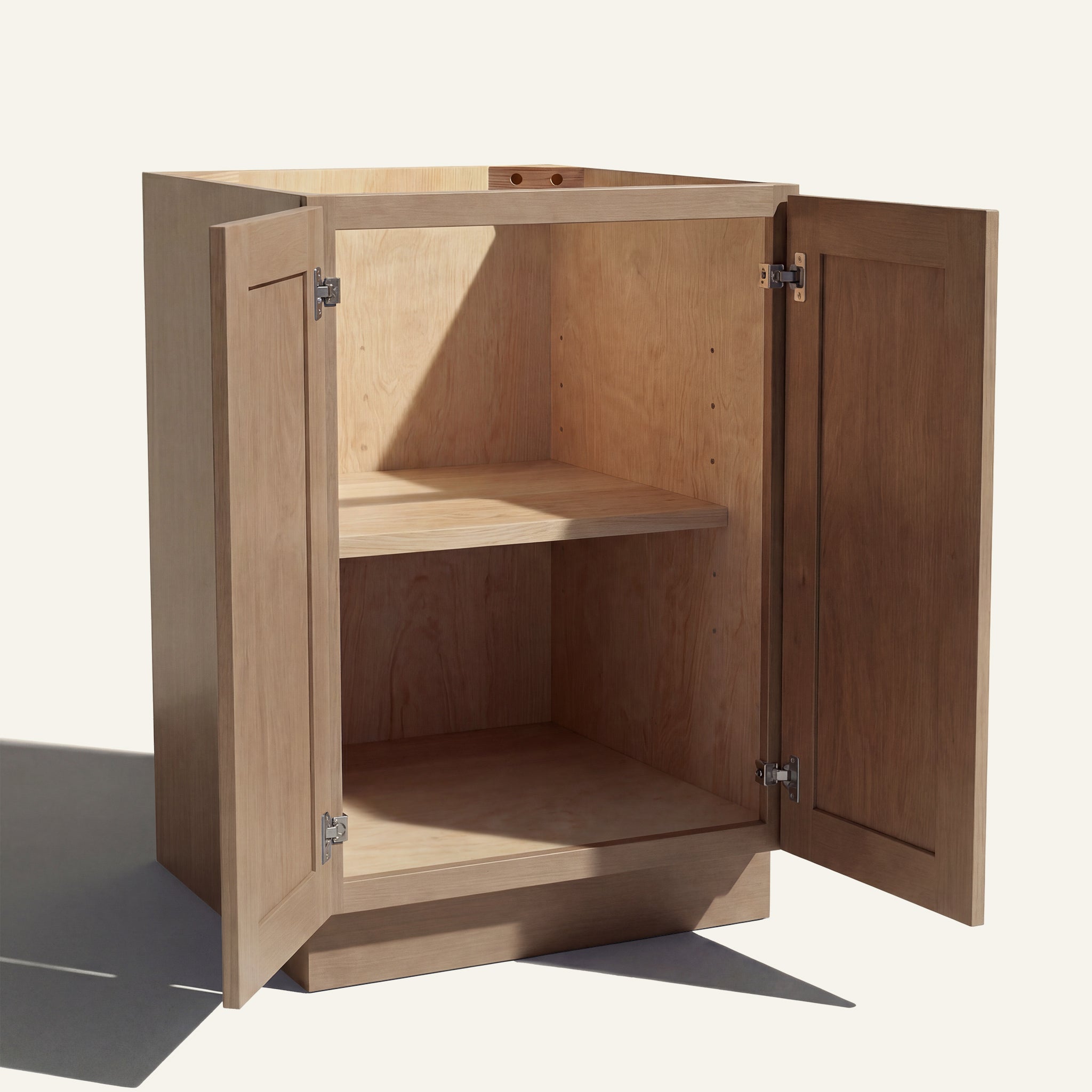 Angled view of a driftwood Seaport Shaker base cabinet with 2 full height doors open showing wood interior and shelf.