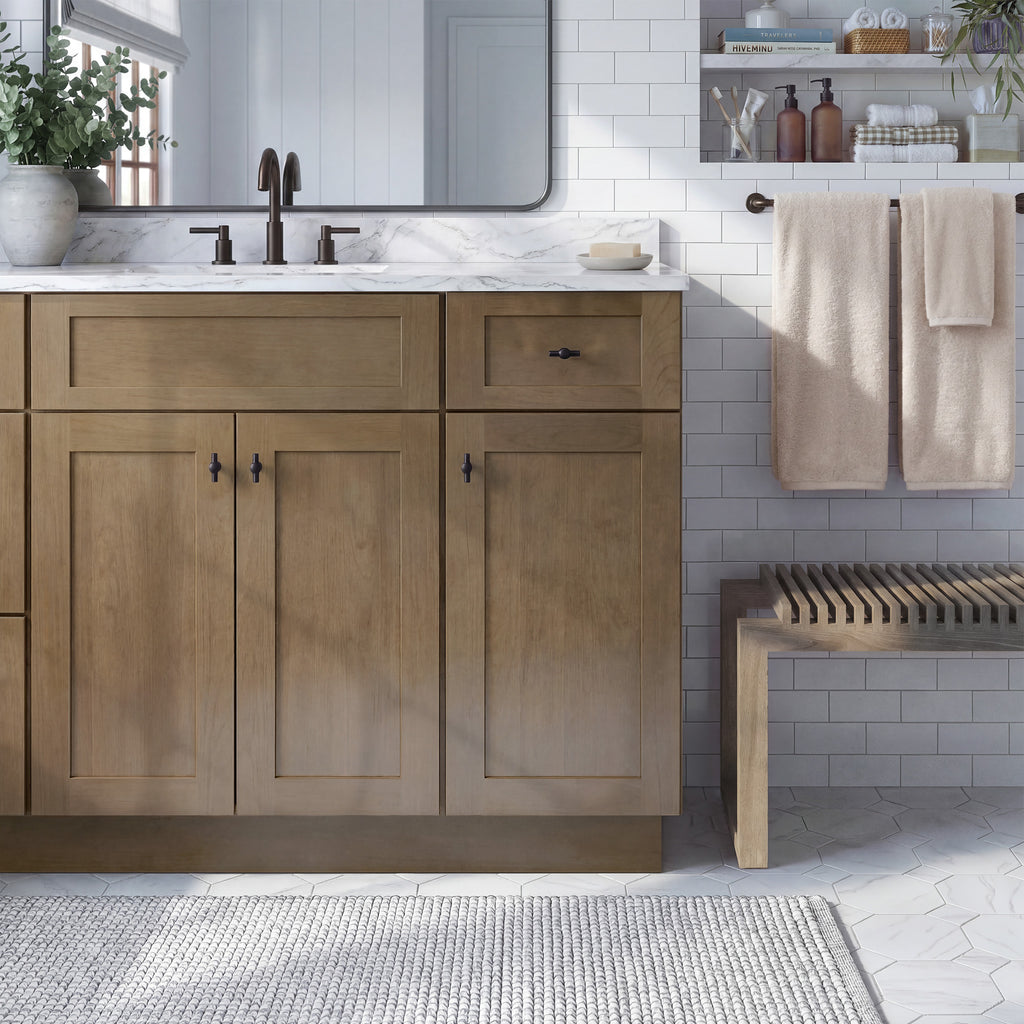 Front view of a driftwood Seaport shaker vanity with 2 doors, 1 drawer, and 1 false front with a nickel latch in a warm bathroom.
