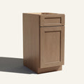 Angled view of a driftwood Seaport Shaker vanity base cabinet with 1 door and 1 drawer.