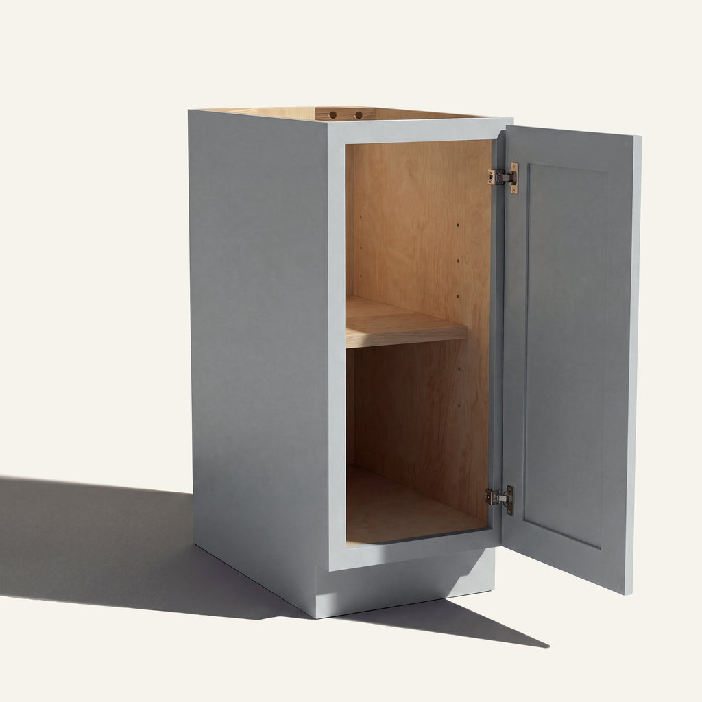 Angled view of a light gray Seaport Shaker base cabinet with 1 door open showing wood interior and shelf.