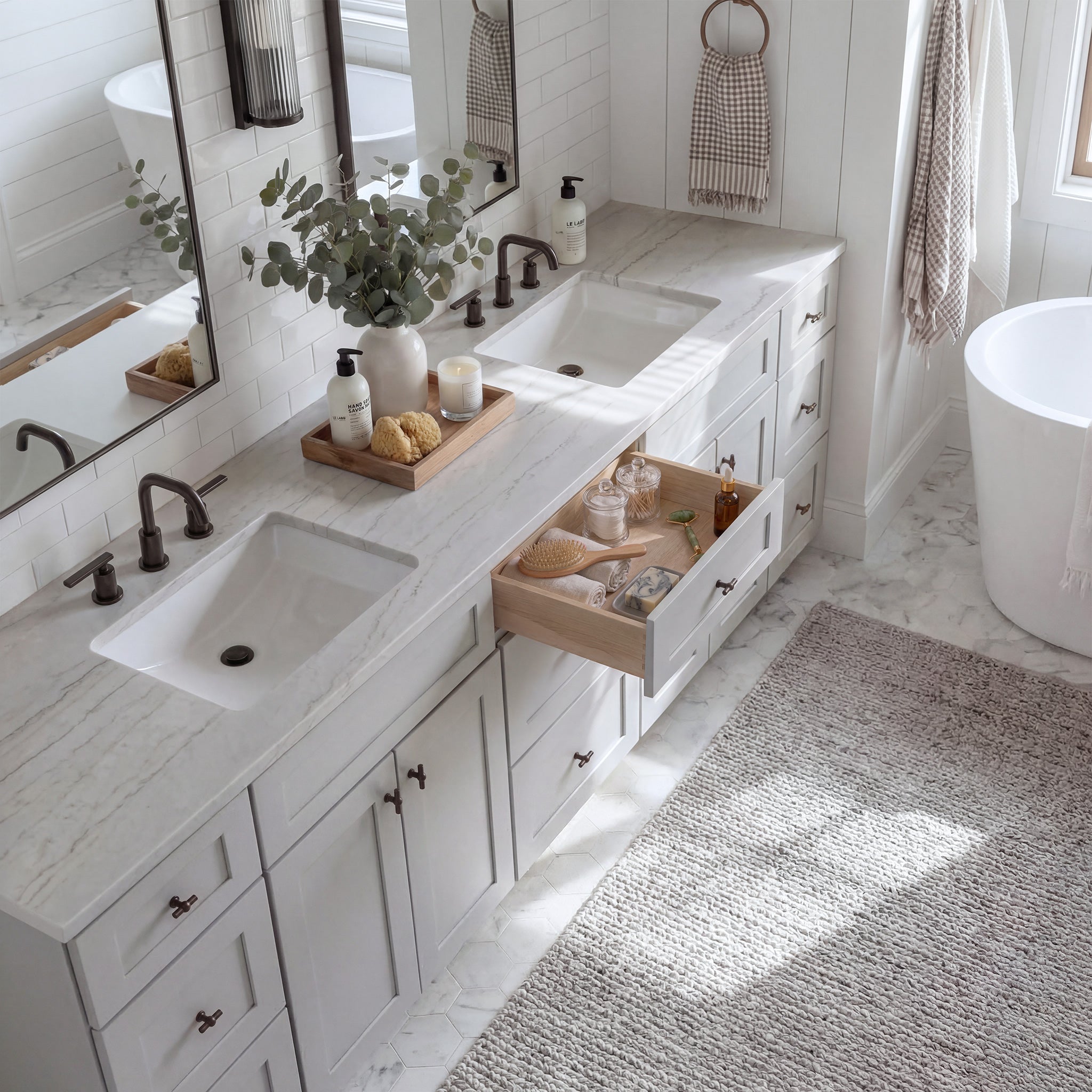 Top-down angled view of a light gray Seaport shaker vanity with an open drawer, lived-in feel, and Mont Blanc quartzite counter.