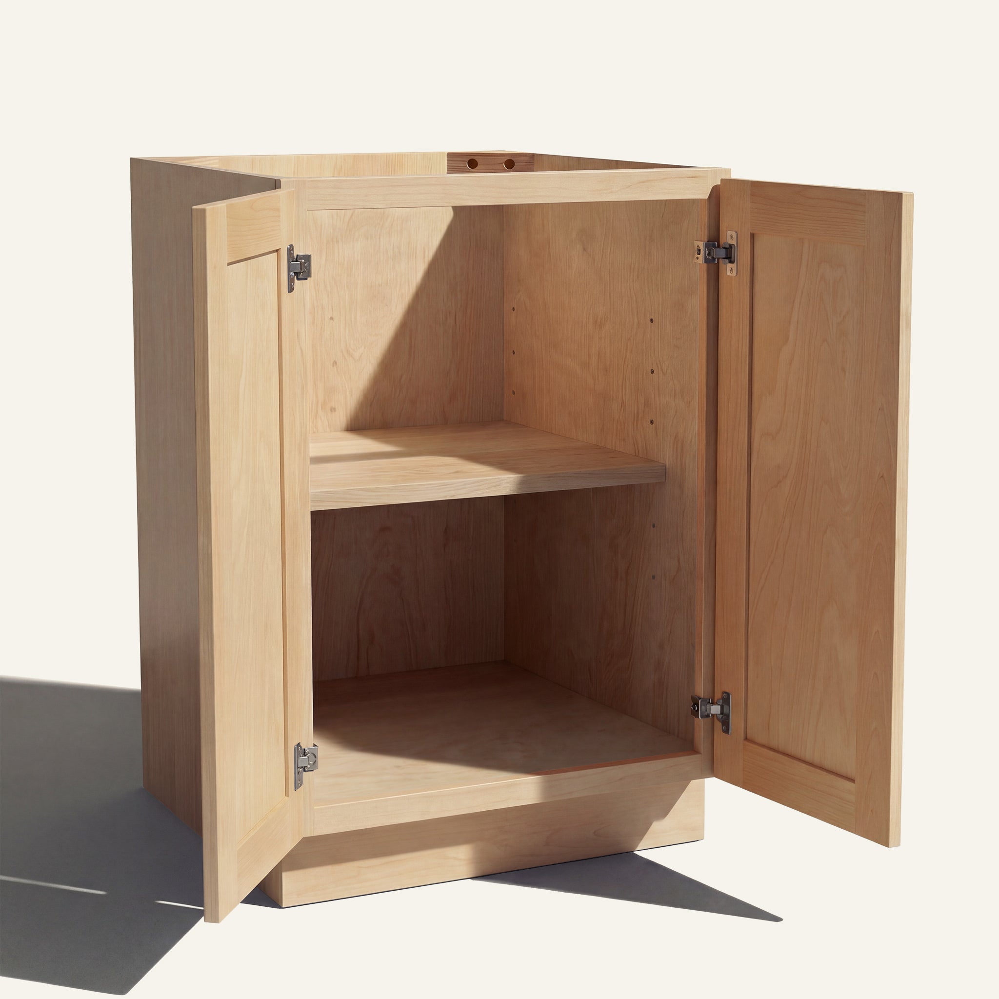 Angled view of a natural Seaport Shaker base cabinet with 2 full height doors open showing wood interior and shelf.