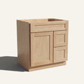 Angled view of a natural Seaport shaker single sink vanity with a left-side door and two right-side drawers.
