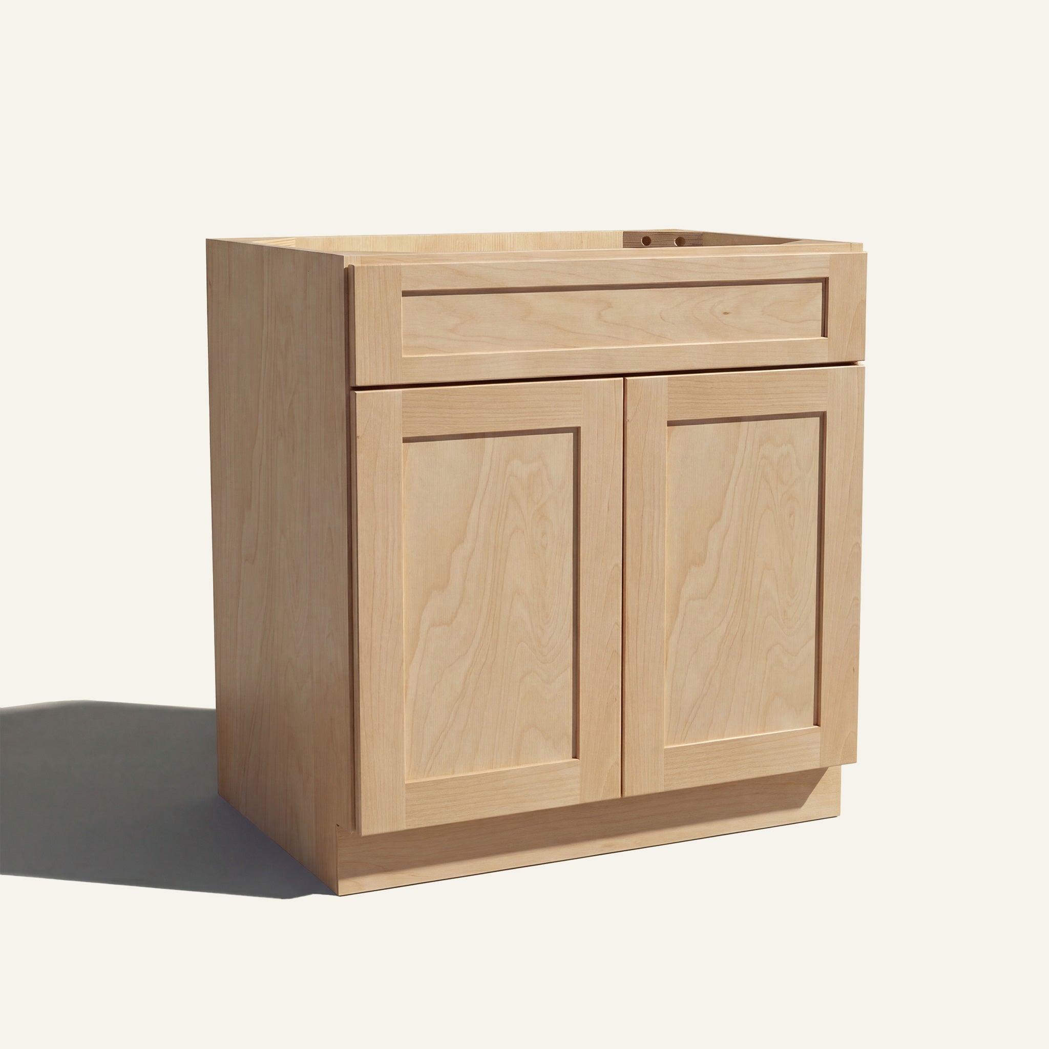 Angled view of a natural Seaport Shaker vanity sink base with 2 doors and 1 false drawer front.