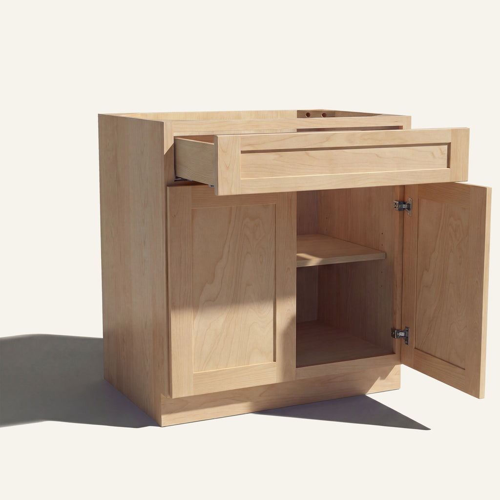Angle view of a natural Seaport shaker base cabinet with 2 doors and 1 open drawer. Right door is open, showing a shelf.