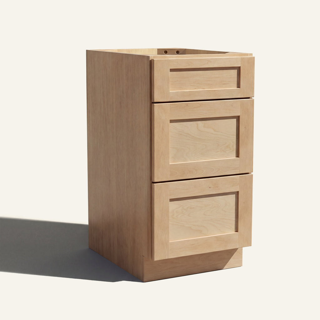 Angled view of a natural Seaport Shaker vanity base with 3 drawers stacked.