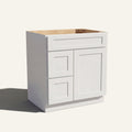 Angled view of a white Seaport shaker single sink vanity with a right-side door and two left-side drawers.
