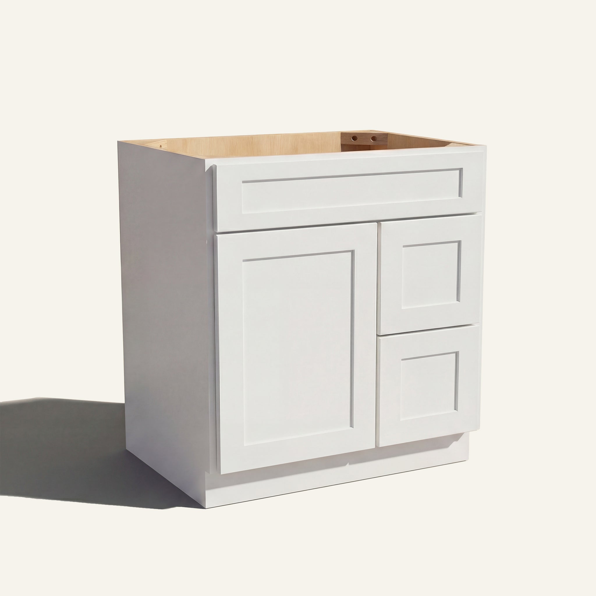 Angled view of a white Seaport shaker single sink vanity with a left-side door and two right-side drawers.