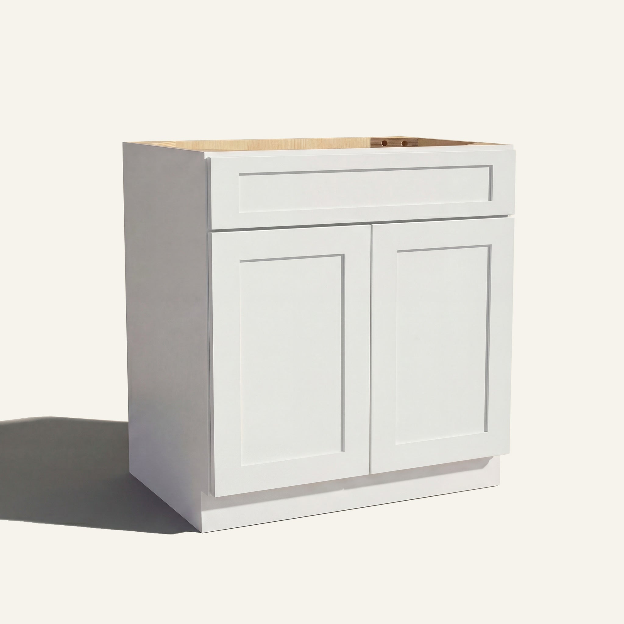 Angled view of a white Seaport Shaker vanity sink base with 2 doors and 1 false drawer front.