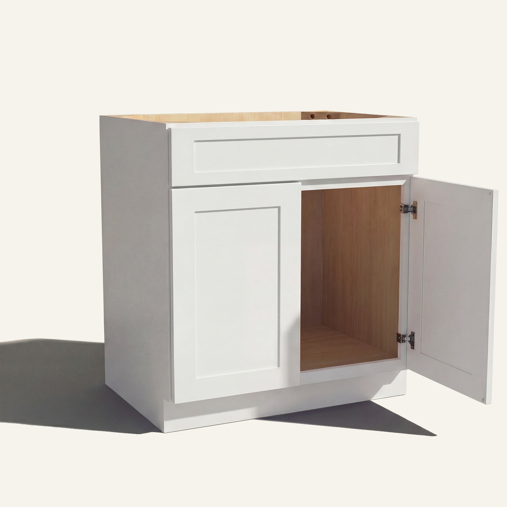Angled view of white Seaport Shaker single sink vanity, 1 false front, 2 doors with right one open to a wood interior.