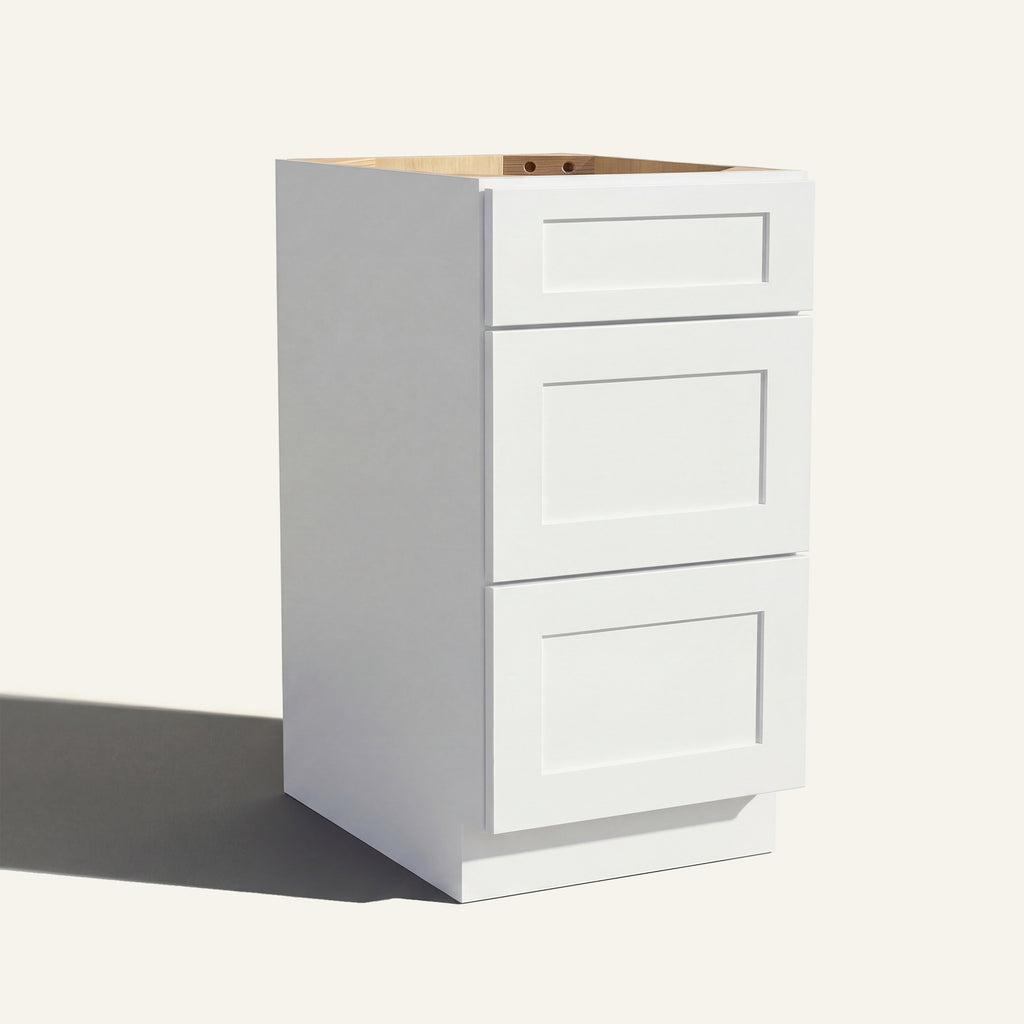 Angled view of a white Seaport Shaker vanity base with 3 drawers stacked.