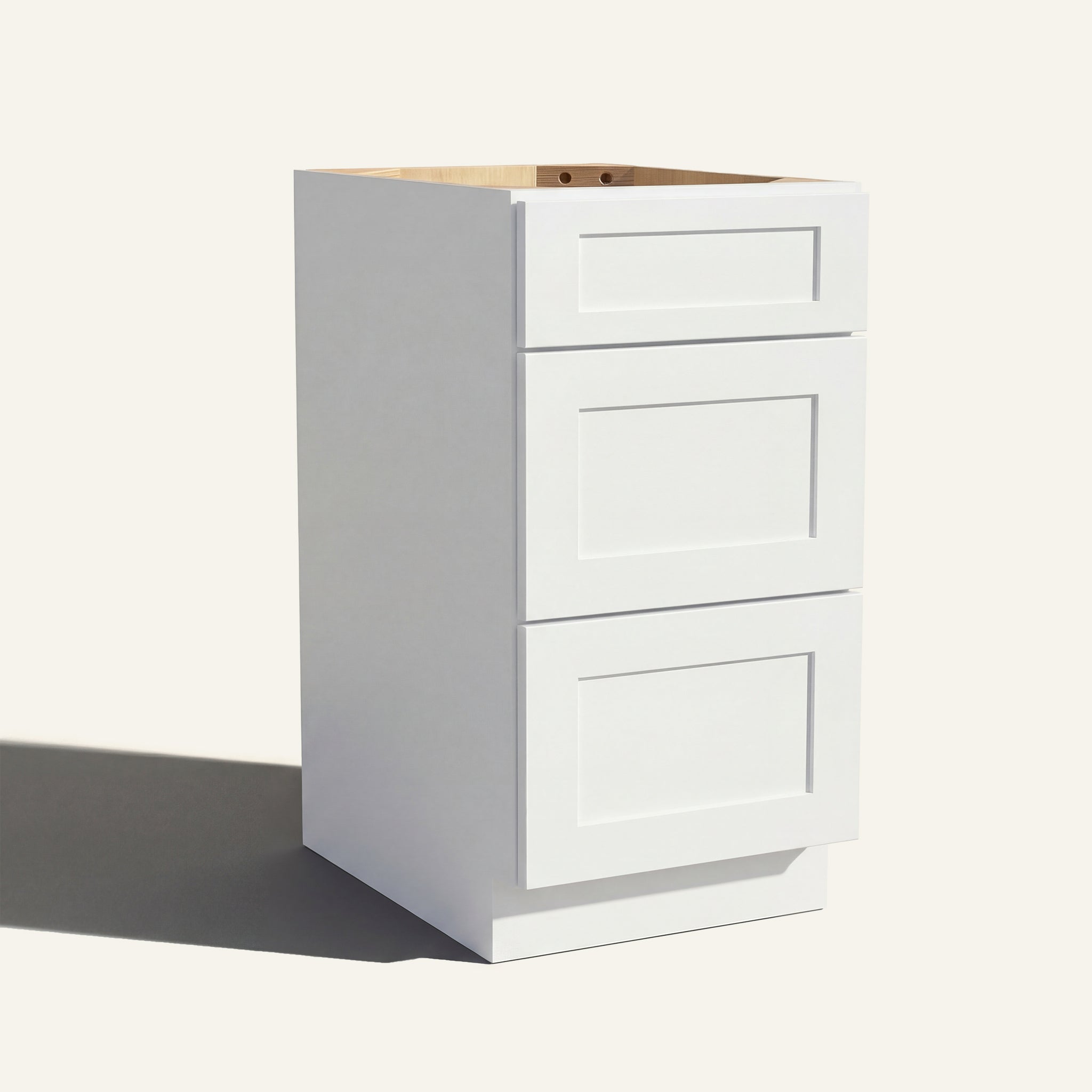 Angled view of a white Seaport Shaker vanity base with 3 drawers stacked.